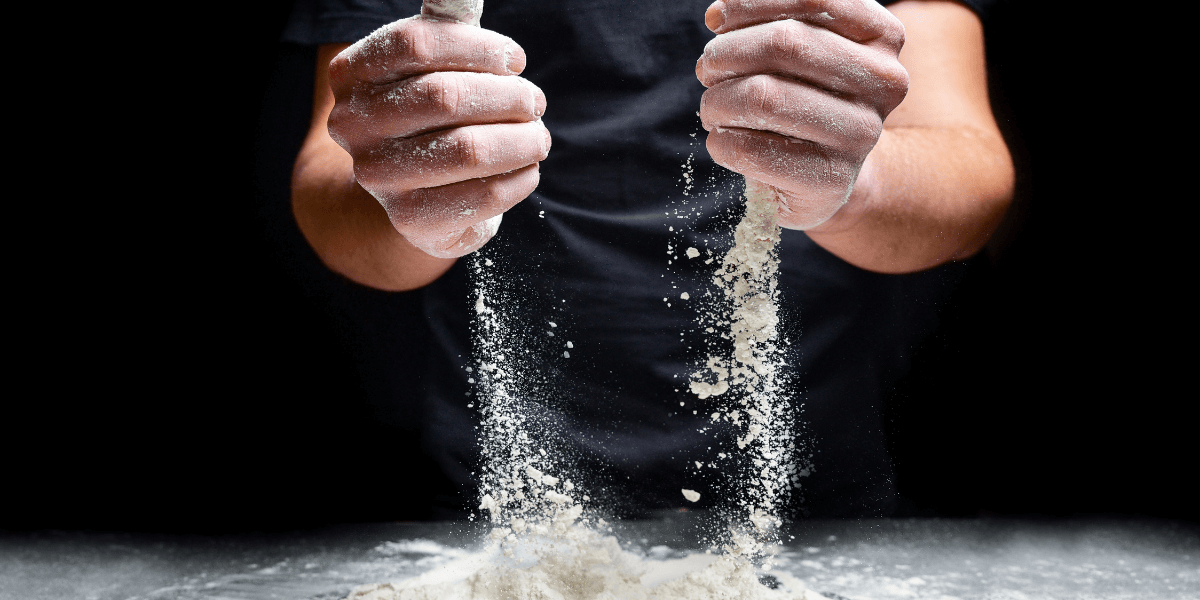 Baker pouring flour onto surface while baking a cake